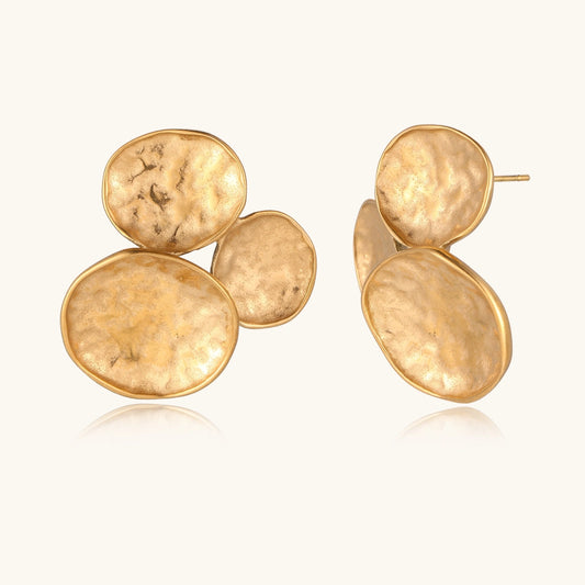 Three hammered gold discs clustered together forming organic statement earrings with textured surfaces