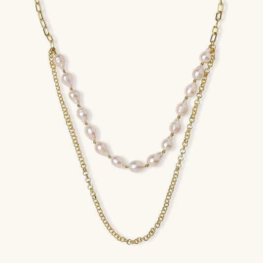 Layered gold chain necklace with organic baroque freshwater pearls and adjustable length on cream background