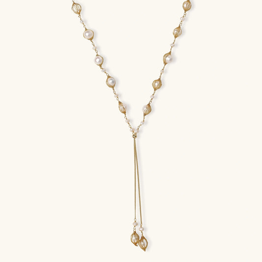 Adjustable gold lariat necklace with freshwater pearls nested in delicate cage settings and Y-shaped tassel drop