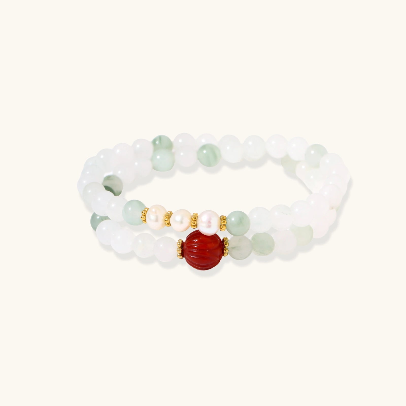 Three layered white beaded bracelets with carved orange agate lotus centerpiece and freshwater pearls on cream background.